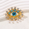 Brosche Auge der Vorsehung mit Goldbeschichtung, blauen Steinen und Perlenanhänger - Blaues Auge-Böhmischer Stil