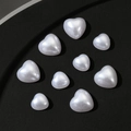 Vista macro di perline bianche a forma di cuore con finitura perlata su nero - Dimensioni miste / Bianco