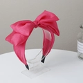 Detail of rose red bow headband with textured fabric on a clear acrylic display stand - Rose Red