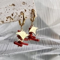 Makro-Detail von goldenen Rochen-Ohrringen mit leuchtend roten Korallen-Akzenten - Manta Rochen