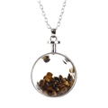 Detailed view of a round glass pendant filled with tiger eye stones on a silver chain - Silver + Tiger's Eye
