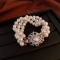 Détail du bracelet de perles multicouche avec fermoir floral argenté sur satin foncé - Bracelet en Perles Multi-rangs avec Fleur Ajourée Argentée