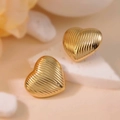 Macro shot of gold heart stud earrings with vertical textured stripes on white stone - Threaded Heart Polished (E0631)