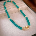 Detail van vintage halsketting met groene jade kralen en gouden dubbele ring gesp op zijde - Blauwe Kralenketting