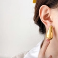 Close-up of a large chunky teardrop earring in polished gold finish on model's ear - Hollow Teardrop (Large) / Gold