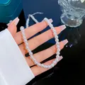 Collier élégant en perles blanches rondes avec fermoir métallique devant un coffret à bijoux - Style Perle 6mm (J101)