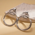 Macro shot of silver layered geometric hoop earrings resting on a textured stone base - Stainless Steel Post - Silver