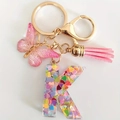 Pink resin letter K keychain with colorful sequins, butterfly charm and pink tassel - Letter K