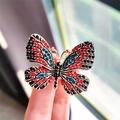 Macro-opname van gouden vlinderbroche met levendige rode en blauwe strasstenen - Groen Rood Zwart Vlinder