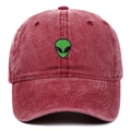 Detailed close-up of green alien embroidery on a washed burgundy cotton baseball cap - Burgundy