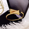 Detail of gold geometric tower bracelet with white crystals on black velvet - Gold + Black