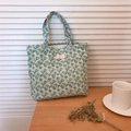 Gros plan du sac en coton avec motifs floraux et étiquette tissée sur table en bois - Vert