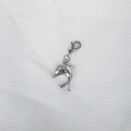 Detailed close-up of a silver dolphin pendant with lobster clasp on white fabric - Small Dolphin