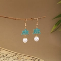 Close-up of green enamel flower earrings with white pearls hanging on a branch - E6408 (Gold/Green Enamel Flower/Pearl)