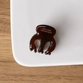 Mini pince à cheveux en acétate marron foncé avec inscription dorée sur une assiette - Chocolat