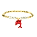 Golden beaded bracelet with white pearls and a red dolphin pendant on a white background - Red