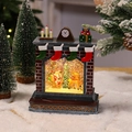 Detailaufnahme einer Weihnachts-Schneekugel mit Kamin und Rentier-Dekoration - Rentier zieht Weihnachtsmann Modell