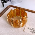 Detail of vintage amber resin segments and gold metal cylinder beads on a wide bangle - Gold Amber Pattern Resin Bangle