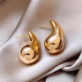 Minimalist golden teardrop stud earrings with a glossy finish on grey silk - Teardrop Geometric Shape / Gold