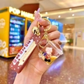 Close-up of brown bubble tea bear keychain with silicone strap and golden bell detail - Milk Tea Bear Mug