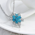 Silver snowflake pendant necklace with blue rhinestones displayed on a ceramic cup - Blue Snowflake