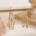 Macro shot of gold layered fringe earrings with cubic zirconia and conical charms - Multi-Layer Tassel Geometric Pendant Earrings (9569) / KC Gold
