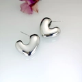 Macro di orecchini a cuore 3D minimalisti in argento su sfondo bianco riflettente - Argento
