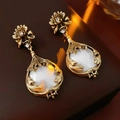 Dettaglio di orecchini vintage dorati con una pietra bianca e accenti di cristallo - Orecchini - Oro