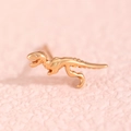 Macro detail of a polished golden Tyrannosaurus Rex stud earring on a pink textured base - Dinosaur Skeleton Style (3686) / Gold