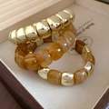 Close-up of three-piece amber resin and gold bead stretch bracelets set on jewelry tray - Light Coffee (Set)