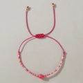 Detalle de una pulsera tejida rosa con cuentas doradas y cordón de seda ajustable - Aventurina Rosa Trenzada