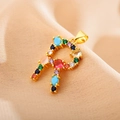 Close-up of golden letter R pendant with multi-colored gemstones on pink silk fabric - Letter R