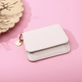 Detailed close-up of white lychee pattern leather wallet with gold ring and round charm - White