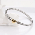 Dettaglio macro del bracciale rigido a cavo intrecciato argento con cuore dorato - Oro 18K / Oro e Argento