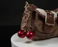 Brown monogram bag with cream wool trim and glittering red cherry charm keychain - Red Cherry with Small Double Leaves (Light Gold)