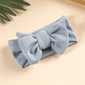 Macro detail of the dusty blue knitted baby headband featuring a textured double bow design - Blue