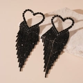 Close-up of black heart earrings with sparkling tassel fringe on natural stone - Black Heart Tassel Style (Silver Pin)