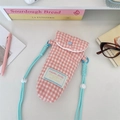 Detailed view of pink plaid quilted camera bag with a bold blue woven shoulder strap - Pink Plaid