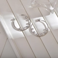 Close-up of silver hoop earrings featuring sparkling cubic zirconia insets on a white stand - Silver