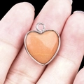 Silver-bordered heart pendant with natural orange gemstone on black background - Pink Aventurine Silver Edging