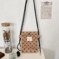 Detailed shot of beige plush crossbody bag featuring red hearts and woven rope strap - Cream Red Heart