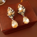 Close-up of vintage amber teardrop earrings with crystals on brown leather base - Gunmetal Black-Coffee