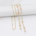 Golden eyeglass chain featuring pink gemstones and zircon accents on white pedestal - 70cm / Champagne