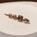 Close-up of golden hair clip with four amber rhinestones in round, square, and teardrop shapes - Style M (Amber)