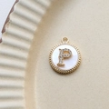 Detail of round gold-plated pendant with shell inlay and zircon letter P on ceramic plate - P Round
