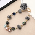 Macro detail of colorful dopamine bead keychain with plush balls and floral metal beads - Black