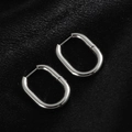 Detail of silver oval hoop earrings with latch-back closure on black silk background - Oval Smooth / Steel