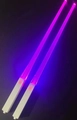Pair of purple glowing LED chopsticks with white handles against dark background - Purple