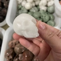Hand-carved white natural stone skull figurine held in hand showing size details - White Jade