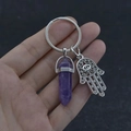 Close-up of Amethyst hexagonal pillar keychain with Hamsa Hand charm being held - Purple Crystal